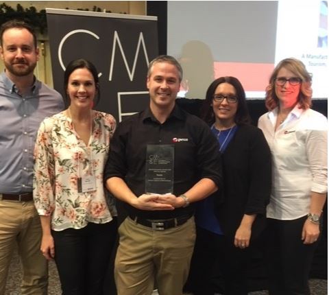 Group of smiling professionals with an award at a conference, standing in front of a CME presentation sign.