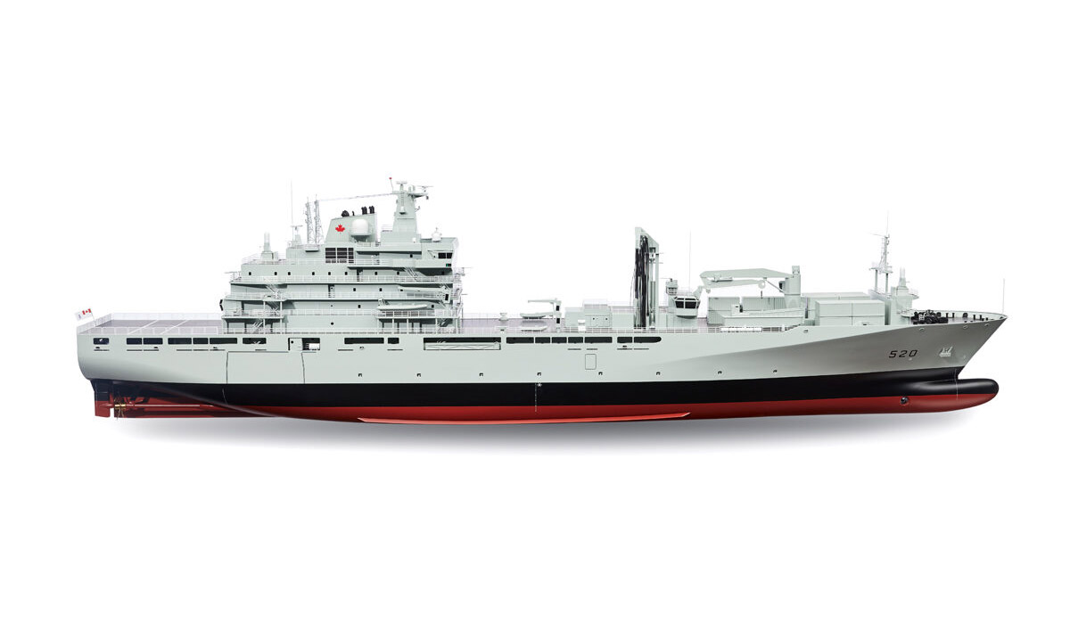 A large military support ship with a grey body, red hull, and multiple decks and equipment visible on the top deck.