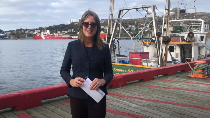 Professional women dressed in black on a wharf in a harbor with ships and the ocean in the background.