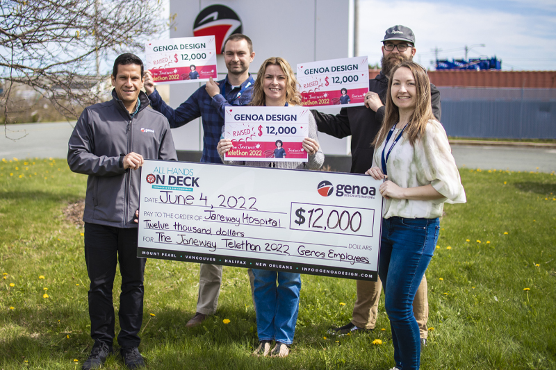 Group of individuals holding large ceremonial checks displaying a donation of $12,000 from Genoa Design to the Janeway Children's Hospital Foundation for the Janeway Telethon 2022, standing outdoors on a grassy area.