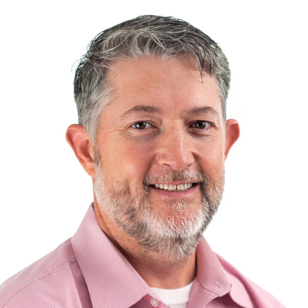 Professional man smiling in a pink shirt, isolated on a white background.